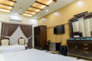 a bedroom with a bed and a mirror and a tv at Patel Residency Guest House in Karachi