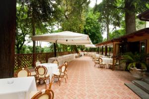 un patio al aire libre con mesas, sillas y sombrillas en Hotel Villa Aricia, en Ariccia