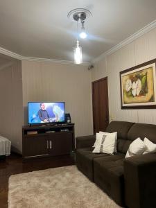 a living room with a couch and a flat screen tv at Equilíbrium Quarto de casal com banheiro compartilhado in Marechal Cândido Rondon