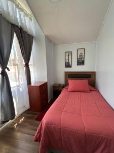 a bedroom with a red bed and a window at Residencial Mar y Sol in Laraquete