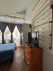 a bedroom with a bed and a television on a dresser at Residencial Mar y Sol in Laraquete