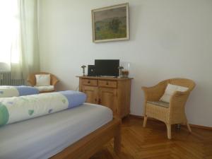 a bedroom with two beds and a desk with a television at Altes Schulhaus in Argenbühl