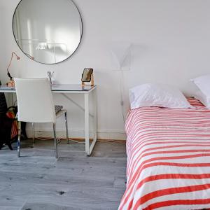 a bedroom with a bed and a desk with a mirror at Appartement Paris vue imprenable in Le Kremlin-Bicêtre
