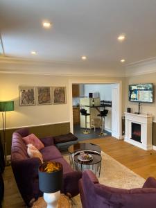a living room with a purple couch and a fireplace at Whisperwood Apartment in Colnrade