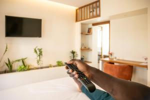 a person holding a remote control in a living room at The Nest - Complimentary Massage Included in Kigali