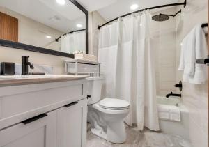 a white bathroom with a toilet and a bath tub at Modern Midtown Studio and Private Balcony in Raleigh