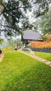 a house with a green lawn and a building at Sinharaja Brook Cabana in Deniyaya