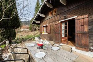 a wooden table and chairs in front of a cabin at Petit chalet l Authentique Annecy in Dingy-Saint-Clair +9 photos