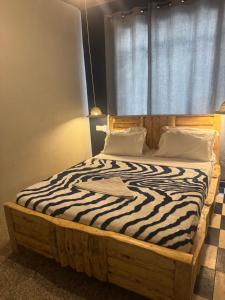 a bedroom with a wooden bed with a zebra print blanket at Woodland villa in Arusha