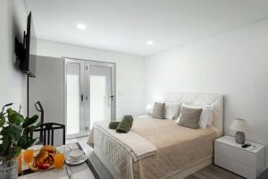 a white bedroom with a bed and a table at OurMadeira - Terrace Sea Apartments in Ribeira Brava