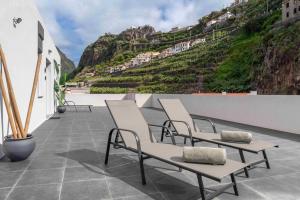 a group of chairs sitting on a patio with a mountain at OurMadeira - Terrace Sea Apartments in Ribeira Brava