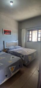 a room with three beds in it with a window at Casa da vila in Imbituba