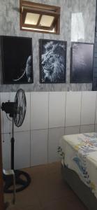 a bedroom with a fan and pictures on the wall at Casa da vila in Imbituba