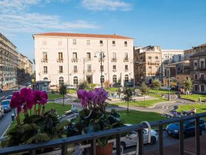 un balcón con flores púrpuras en una calle de la ciudad en B&B Sciara Larmisi, en Catania