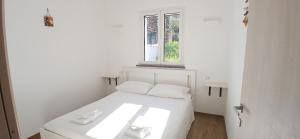 a white bed in a white room with a window at Sa Zirighetta in S'archittu Cuglieri