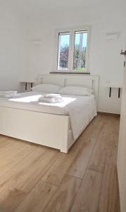a large white bed in a room with a wooden floor at Sa Zirighetta in S'archittu Cuglieri