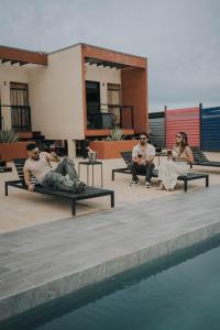 a group of people sitting on benches next to a pool at Casas VV in Valle de Guadalupe