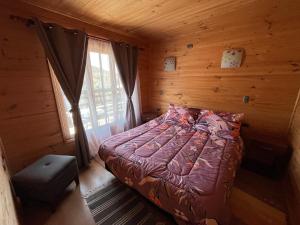 a bedroom with a bed in a log cabin at Cabañas Sra Mery in Quilimarí