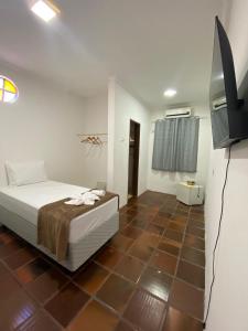a bedroom with a bed and a flat screen tv at Santa Ana da Ribeira in SantʼAnna do Ipanema