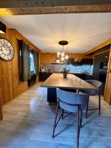 a kitchen with a table and chairs and a clock at Chalet le Bô & Spa in Bussang