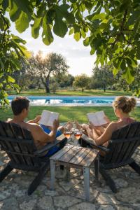 a man and woman sitting in chairs reading books at I Mulicchi in Specchia