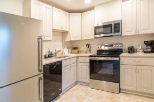 a kitchen with white cabinets and black appliances at Bright, Spacious Home with Private Deck in Potomac +4 photos