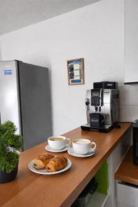 two cups of coffee and croissants on a kitchen counter at Le Colibri in Fenouillet