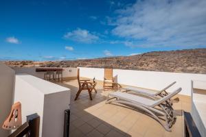 eine Terrasse mit Stühlen und einem Tisch auf einem Dach in der Unterkunft Salitre in Ajuy