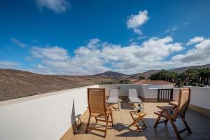 eine Terrasse mit Stühlen und einem Tisch an einer Wand in der Unterkunft Salitre in Ajuy
