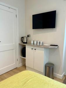 a room with a tv on a wall with a table at Acorns in Hordle