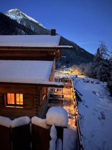 a log cabin with snow on the roof at night at Chalet am Bachl 2 in Flattach +17 photos