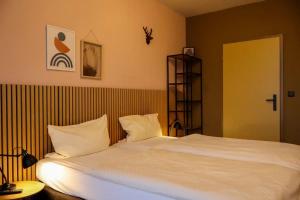 a bedroom with a large bed with white sheets at Airport Hotel Jägerhof Weeze in Weeze