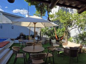 a patio with tables and chairs and an umbrella at Real Hotel in Sete Lagoas