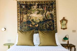 a tapestry hangs above a bed with pillows at Boutique Apartment nel Borgo - Casa Olga e Casa Ilde - Le Dimore del centro in Santarcangelo di Romagna +20 photos