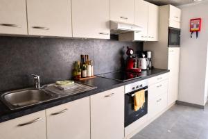 a kitchen with white cabinets and a sink at Au Chant des Roches Gîte en pierre avec jardin à Cerfontaine in Cerfontaine