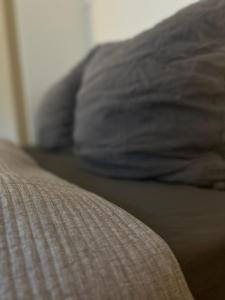 a close up of a bed with gray sheets and pillows at Goodie Room I Apartment I Würzburg Estenfeld in Estenfeld