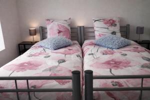 two beds in a bedroom with pink flowers at Au Chant des Roches Gîte en pierre avec jardin à Cerfontaine in Cerfontaine