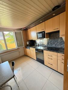 a kitchen with wooden cabinets and black counter tops at Large room, shared kitchen and bath, near station in Bolligen