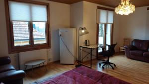 a living room with a refrigerator and a table at Large room, shared kitchen and bath, near station in Bolligen