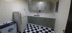 a kitchen with a refrigerator and a checkered floor at شقة مفروشة غرفة وصالة بالمبرز in Al Mubarraz
