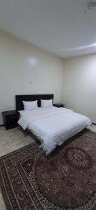 a bedroom with a large white bed with a rug at شقة مفروشة غرفة وصالة بالمبرز in Al Mubarraz