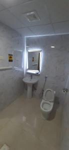 a bathroom with a toilet and a sink and a window at شقة مفروشة غرفة وصالة بالمبرز in Al Mubarraz