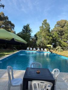 a table and chairs next to a swimming pool at Viento Potro Casa Quinta de Campo in San Miguel del Monte