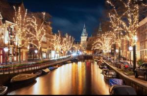 a city at night with boats in a canal at Maison Lumière - Private Rooftop terrace in Amsterdam