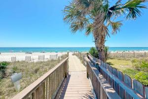 a wooden pathway to the beach with a palm tree at Grand Caribbean East Poolside Palms in Pensacola