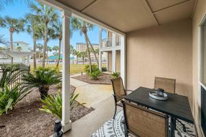 a patio with a table and chairs and palm trees at Grand Caribbean East Poolside Palms in Pensacola