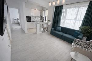 a living room with a blue couch and a kitchen at Solid Residence Apartamente in Mamaia +85 photos