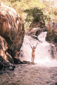 a person standing on a rock in a waterfall at Hotel Hukumeizi Minca in Minca