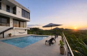 a villa with a swimming pool and an umbrella at Arrayanes 33, Ricaurte San Marcos in Ricaurte