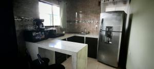 a kitchen with a stainless steel refrigerator and a table at Arenal Jendrik house in Agua Azul
